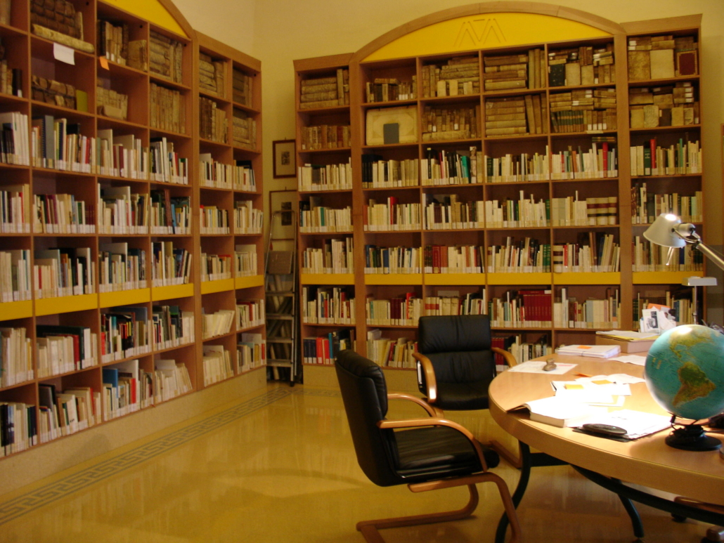 Sala interna della biblioteca comunale con scaffali di libri antichi ed una scrivania per la consultazione